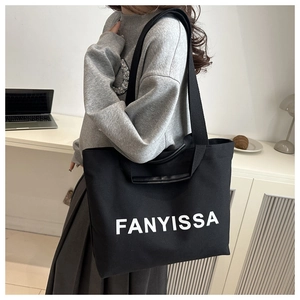 Vue détaillée d'un grand sac cabas en toile noire avec logo FANYISSA blanc imprimé