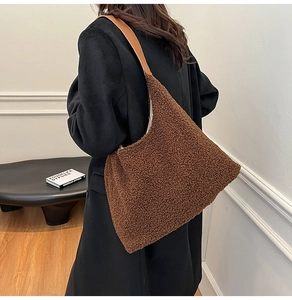 Detail view of the brown plush tote bag with leather strap worn over a shoulder