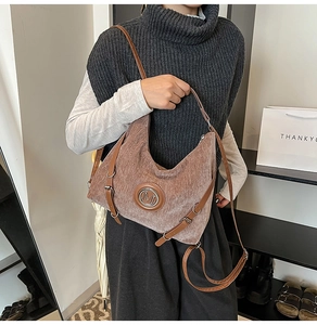 Détail d'un sac cabas demi-lune marron texturé avec logo M et bandoulière en cuir