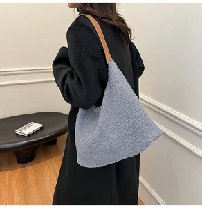 Detail of blue faux shearling tote bag with brown leather strap worn with black coat