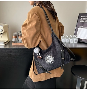 Détail du grand sac cabas noir texturé avec logo M en métal argenté et pompon en peluche blanc