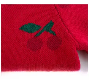 Detailed close-up of red knit sweater featuring a green-leafed cherry jacquard pattern