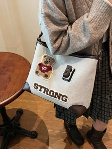 Cute cartoon canvas tote bag with brown leather trim and teddy bear patches shown on model