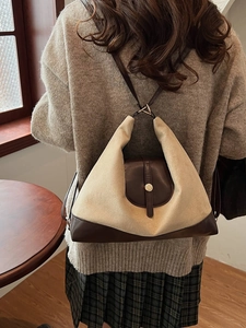Sac cabas vintage en tissu beige avec garniture en cuir marron porté par un modèle