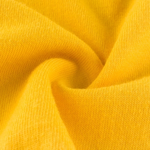 Gros plan sur le tissu en tricot de coton jaune gingembre pour t-shirt fille