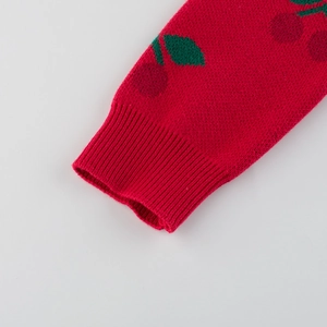 Red girls' knit sweater featuring cherry patterns with ribbed cuffs in a close-up view