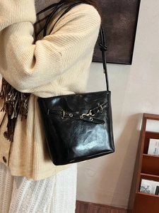 Retro black leather shoulder bag with gold hardware worn by a model in autumn outfit