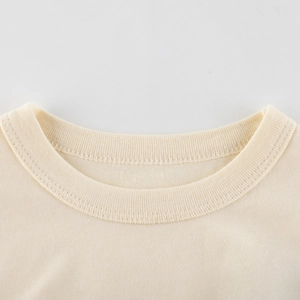 Gros plan sur un T-shirt beige en coton pour filles avec col rond côtelé et surpiqûres