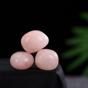 Set of three polished rose quartz tumbled stones displayed on a black textured surface