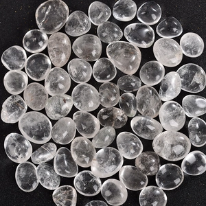 Polished clear quartz tumbled stones for home decor and healing scattered on black texture