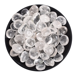Polished natural clear quartz tumbled stones in a black bowl for healing decor