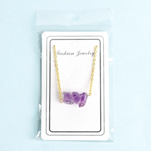 Minimalist gold necklace with three purple natural raw stones on a display card