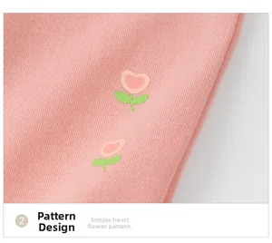 Dettaglio di morbido tessuto in maglia rosa con stampa floreale a cuore per bambini