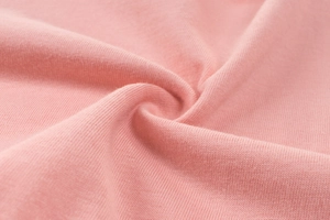 Primo piano del morbido tessuto in maglia di cotone rosa con trama fine e pieghe