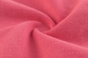 Macro shot of high-quality pink knit fabric showing detailed texture of girls' sports pants