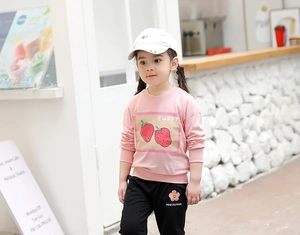 Détail du sweat rose aux fraises et du pantalon de jogging noir brodé de fleurs