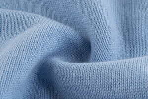 Macro texture of soft light blue knit fabric with high-quality flat stitch weaving details