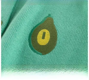 Detailed close-up of avocado embroidery on mint green knit cardigan with fine texture