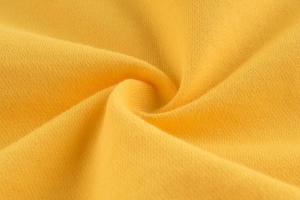 Vue détaillée du tissu en maille jaune vif montrant la texture douce et le tissage fin