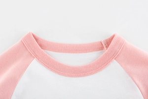 Dettaglio del girocollo raglan con cuciture di qualità su una maglietta in cotone rosa bimba