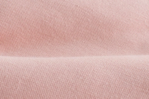Close-up of soft light pink knit fabric texture with high-quality fleeced finish