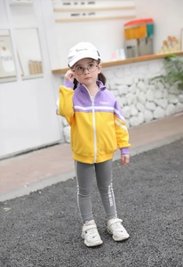 Girl in purple and yellow zipper jacket with grey fashion leggings and baseball cap