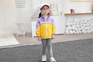 Detail view of girls' purple and yellow zipper jacket with 'HAPPY' print and slim grey pants