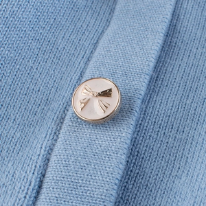 Close-up of light blue girls' knit cardigan with a golden bow-tie decorative button