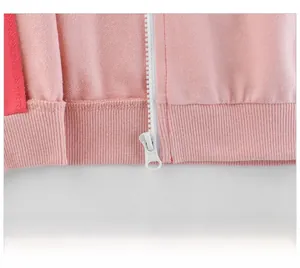 Detail of pink zip-up hoodie featuring ribbed hem and contrasting red side panel