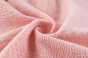 Close-up of soft pink knit fabric texture showing the delicate weave on girls hoodie