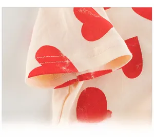Détail de la manche d'un T-shirt enfant crème avec motif cœur rouge et coutures précises