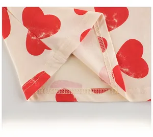 Détail de l'ourlet à double couture et motif cœur rouge sur T-shirt enfant écru