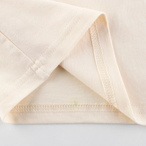 Close-up of double-needle stitching and fine knit texture on apricot cotton t-shirt hem