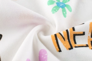 Détail macro du tissu en maille de coton doux avec motifs floraux et lettrage orange