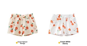 Detail of girls' cotton shorts with elastic waistband and orange or cherry patterns