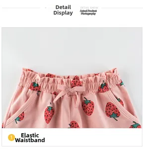 Detail of girl's pink strawberry print shorts featuring elastic waist and bow decor