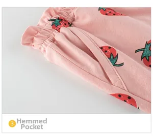 Close-up of strawberry print pink cotton shorts showing elastic waist and hemmed pockets