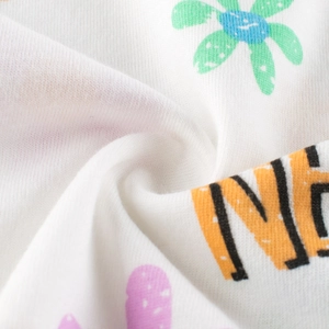 Gros plan sur le tissu en coton blanc du t-shirt avec motifs floraux et lettres oranges