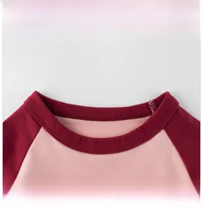 Detail show of the pink and burgundy round neckline on this girls' cotton long sleeve top