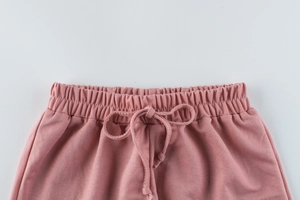 Detailed close-up of elastic waistband with drawstring on pink knit girls' shorts