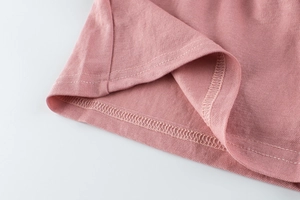 Macro detail of high-quality double-needle stitching on pink piqué knit trousers