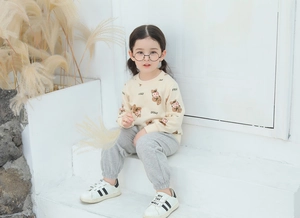 Detail of children's cotton tracksuit with bear prints and grey jogger pants on model