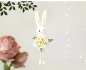 Detail of Easter bunny plush with floral ears and cream flower pendant decoration