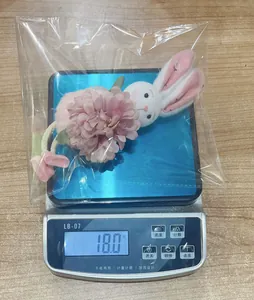 Dettaglio del ciondolo a forma di coniglietto pasquale e fiore rosa in borsa di plastica