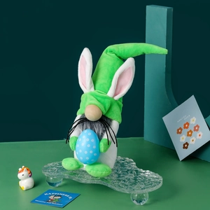Gnome de Pâques en peluche verte avec oreilles de lapin tenant un œuf bleu à pois