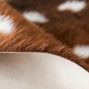 Detail shot of the faux sika deer fur rug texture with dense brown and white spotted pile