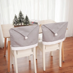 Detail of grey non-woven Christmas hat chair covers with white pom-pom for dining chairs