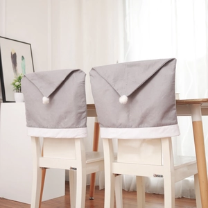 Detail view of two grey Nordic-style Christmas chair covers with white plush pompoms
