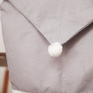 Detail of grey non-woven Christmas chair cover with white fluffy pompom decoration