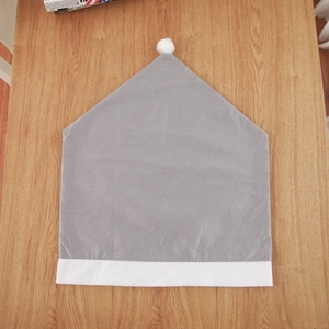 Detail of grey non-woven Christmas chair cover with white plush trim and pom-pom ball